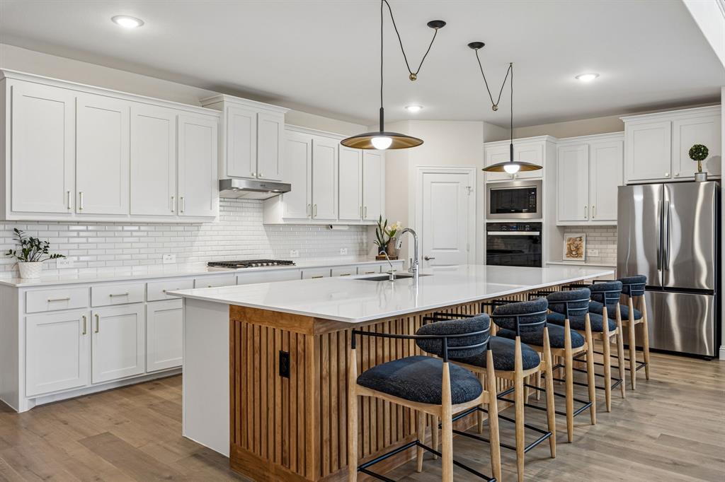 425 Breeds Hl Road Little Elm, TX 75068 - Photo 5 of 38 a kitchen with stainless steel appliances a stove a sink dishwasher a refrigerator with white cabinets and wooden floor