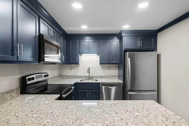 a kitchen with stainless steel appliances granite countertop a refrigerator a stove a sink and a microwave