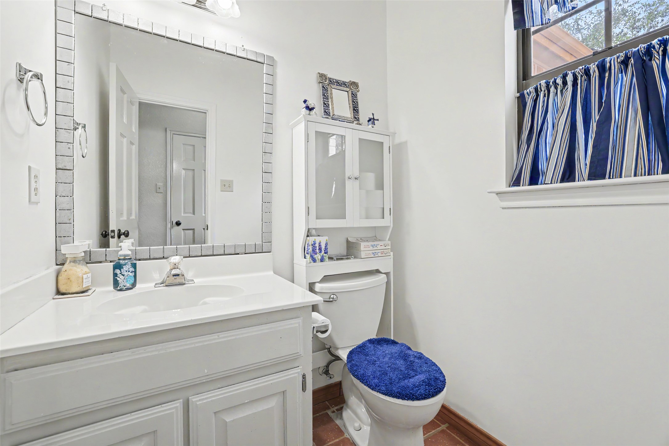 110 South Ridge Circle Georgetown, TX 78628 - Photo 26 of 37 Bathroom featuring a vanity with an integrated sink, a large mirror with a tile frame, a window, and terra cotta-style flooring