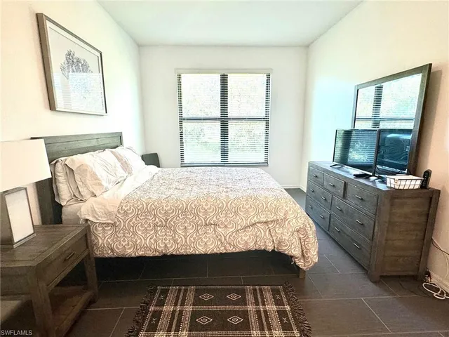 a bedroom with a bed and a flat tv screen on dresser