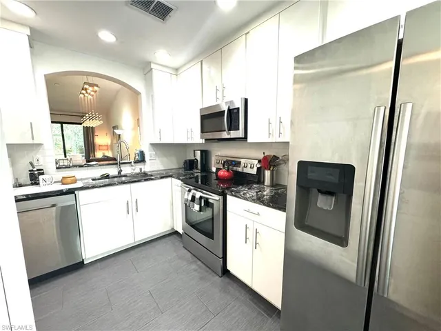 a kitchen with stainless steel appliances granite countertop a refrigerator a stove a sink and a microwave