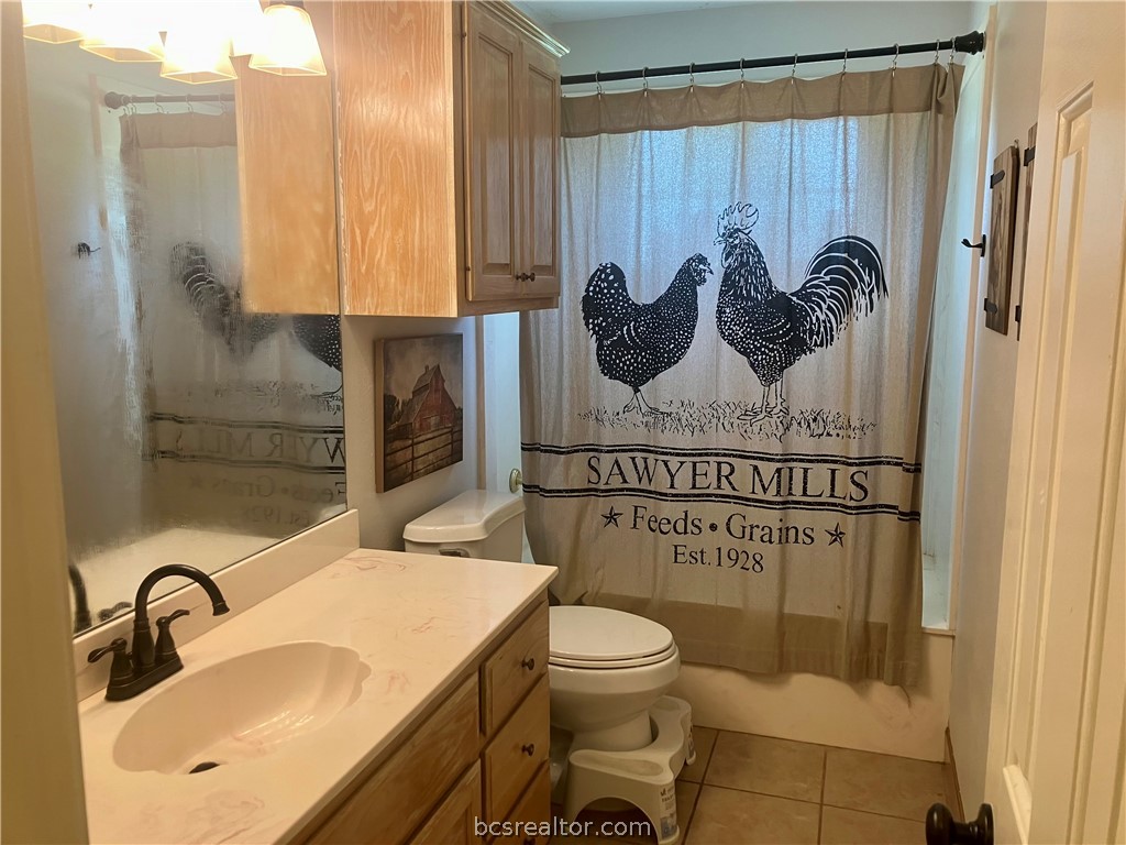 5660 Falling Water Bryan, TX 77808 - Photo 21 of 27 Full bathroom with toilet, vanity, tile patterned floors, and shower / tub combo with curtain