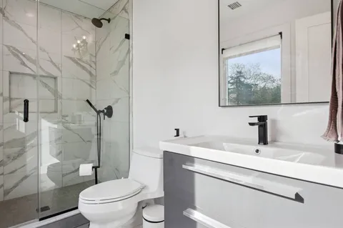 a bathroom with a sink a toilet and shower