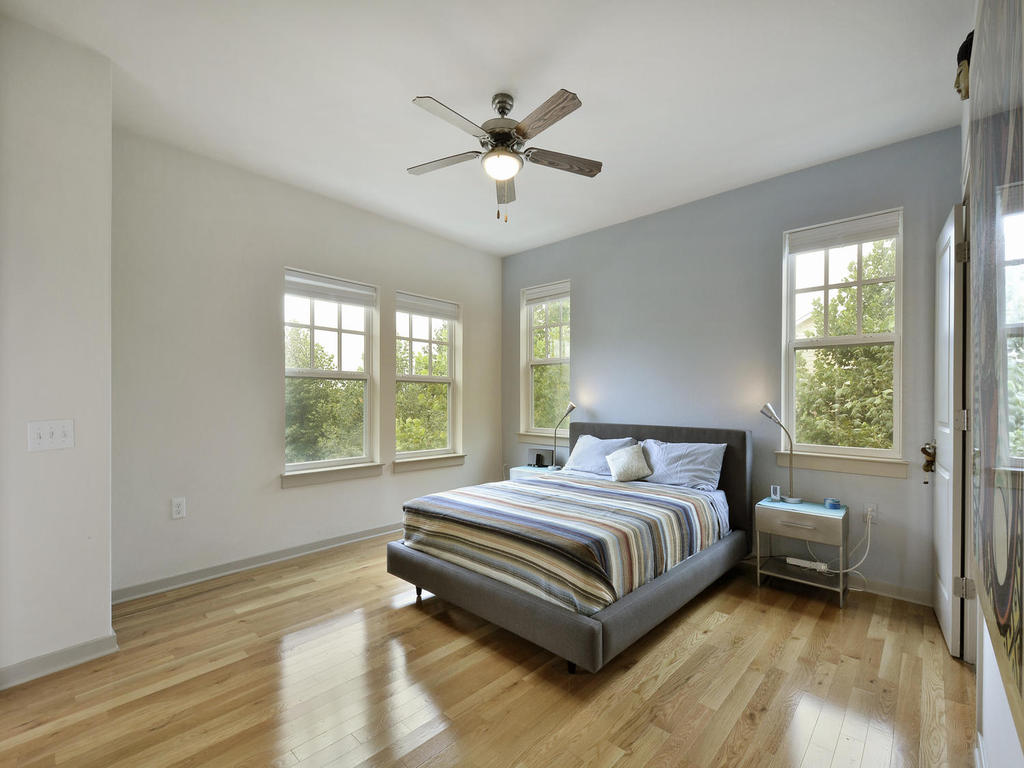 3900 Threadgill Street, Unit 32 Austin, TX 78723 - Photo 19 of 30 Gleaming hardwood floors and multiple large windows define this bright, airy bedroom.