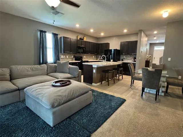 a living room with furniture kitchen view and a wooden floor