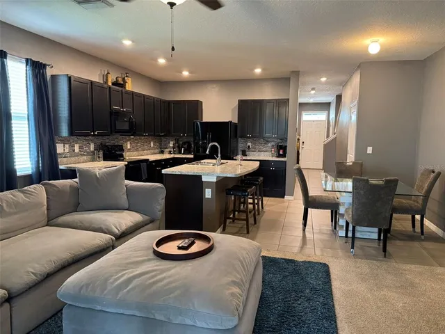 a living room with stainless steel appliances furniture a rug and a kitchen view