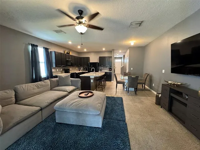a living room with furniture kitchen and a flat screen tv