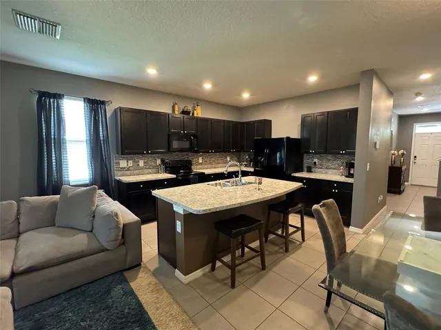 a living room with stainless steel appliances kitchen island furniture a flat screen tv and a kitchen view