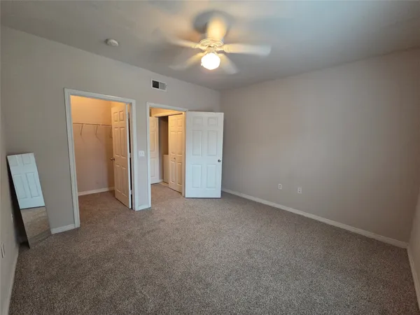 an empty room with closet and a ceiling fan