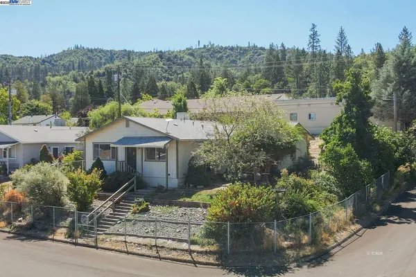 a front view of a house with a yard and mountain view in back
