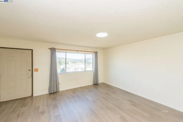 an empty room with wooden floor and window