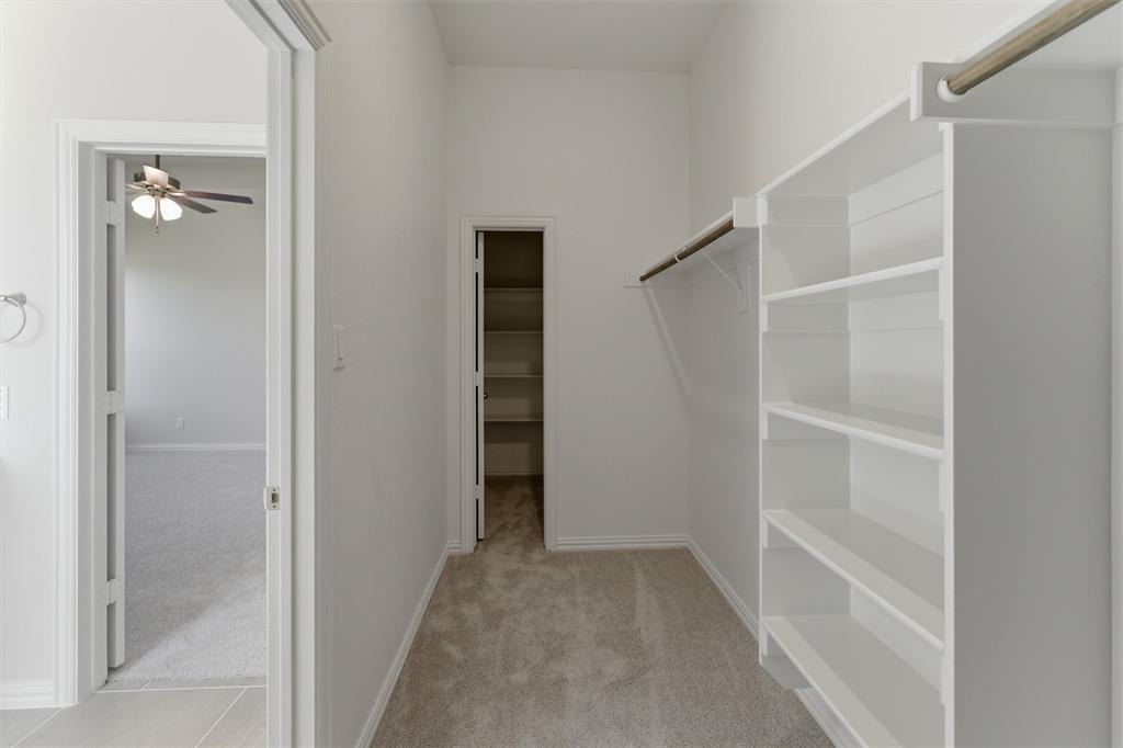 104 Snowy Owl Trail Rhome, TX 76078 - Photo 21 of 27 Walk-in closet featuring built-in shelving, hanging rods, and carpet flooring