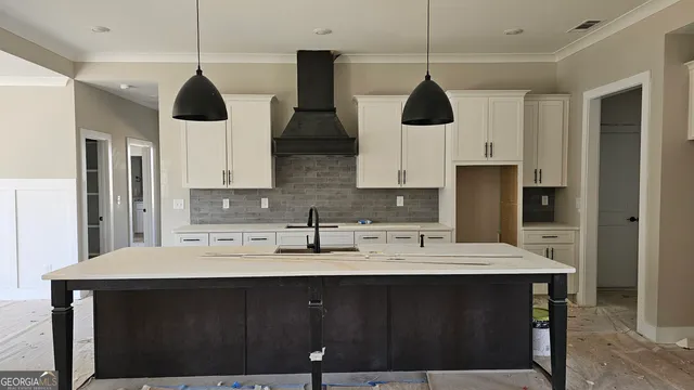 a kitchen with stainless steel appliances a sink a refrigerator a center island and cabinets