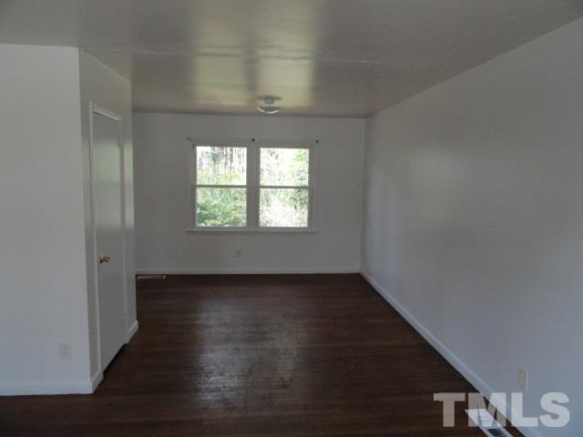 924 Friar Tuck Road Raleigh, NC 27610 - Photo 3 of 5 an empty room with wooden floor and windows