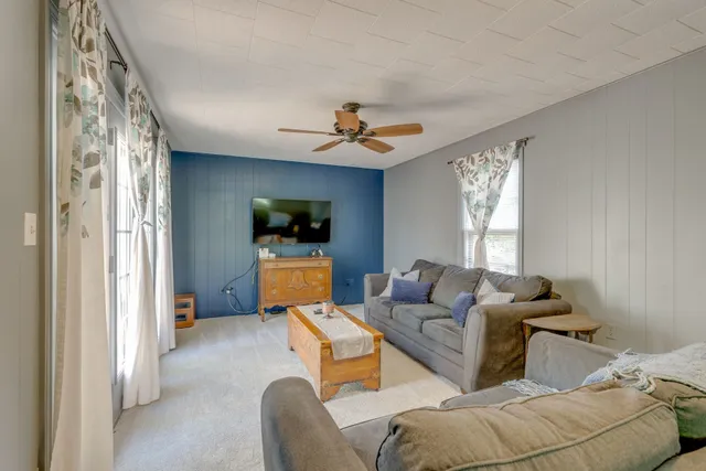 a living room with furniture a ceiling fan and a window