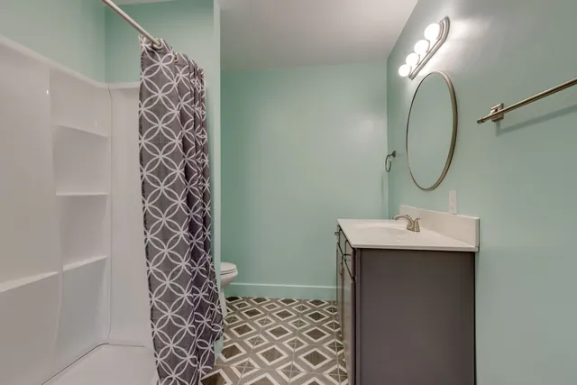a bathroom with a sink a light fixture and shower