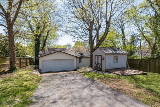 a front view of a house with a yard and large tree