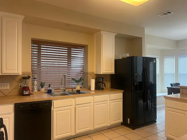 a living room with stainless steel appliances lots of furniture and a kitchen view