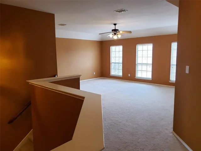 en empty room with windows and ceiling fan