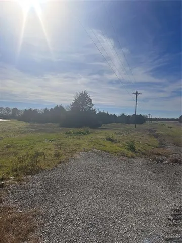 a view of dirt field with large trees