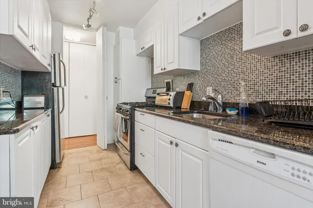 a kitchen with granite countertop white cabinets and white appliances