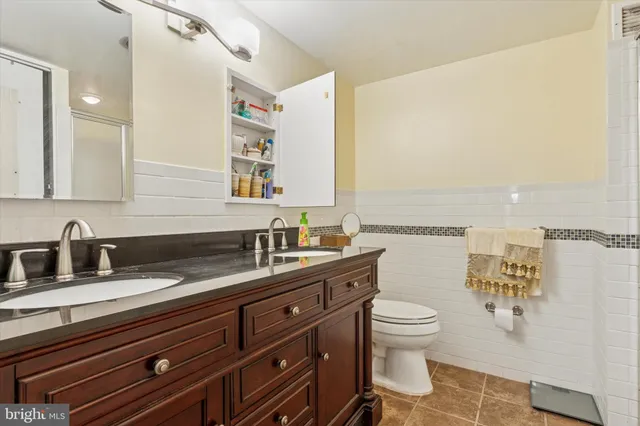 a bathroom with a granite countertop sink a toilet and a mirror