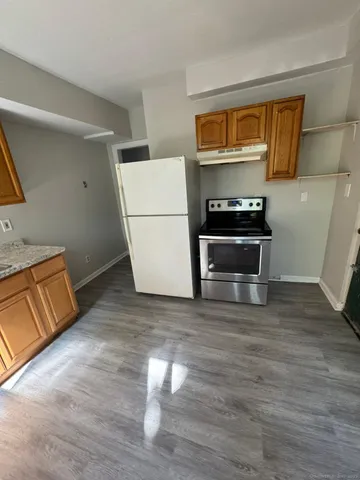 a living room with stainless steel appliances wooden floor and a fireplace