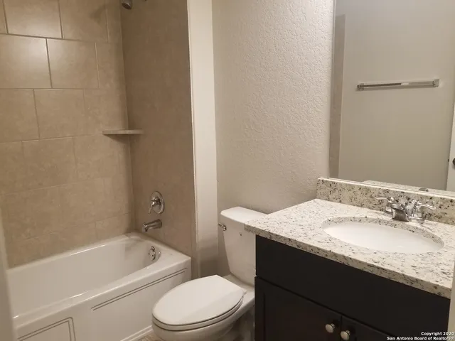 a bathroom with a granite countertop sink a toilet and bathtub