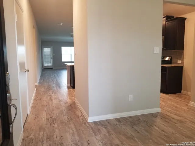 a view of a hallway with wooden floor and a bathroom