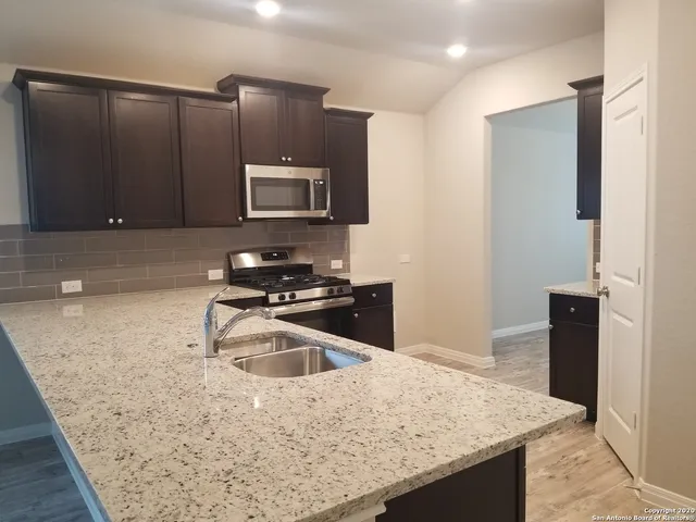 a kitchen with granite countertop a sink and a stove top oven