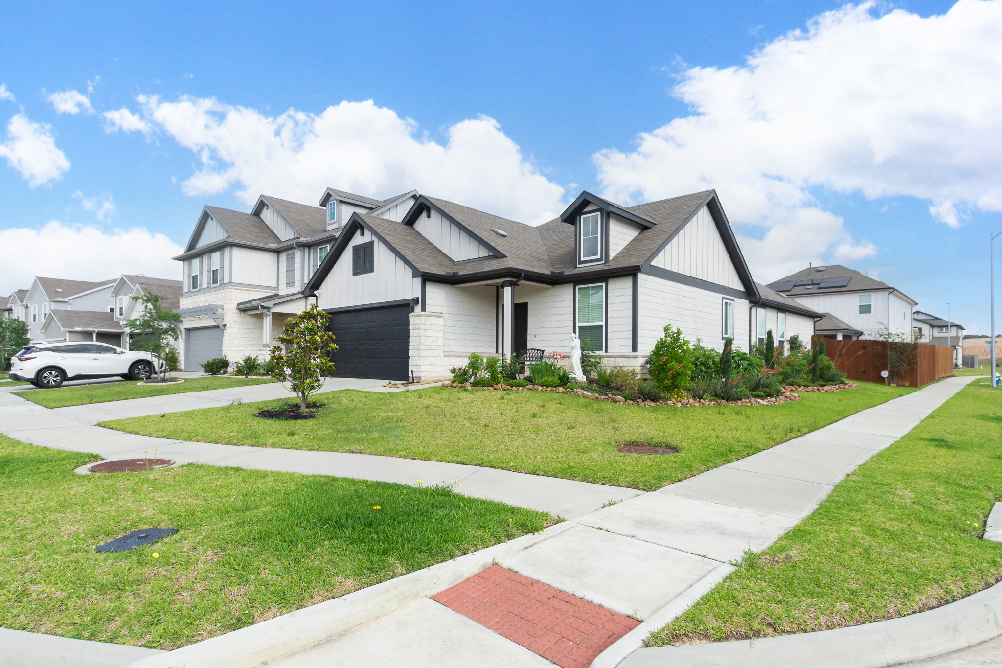 Charming modern home on a spacious corner lot with well-maintained landscaping and a welcoming front porch. Features a double garage and a sleek design in a suburban neighborhood.