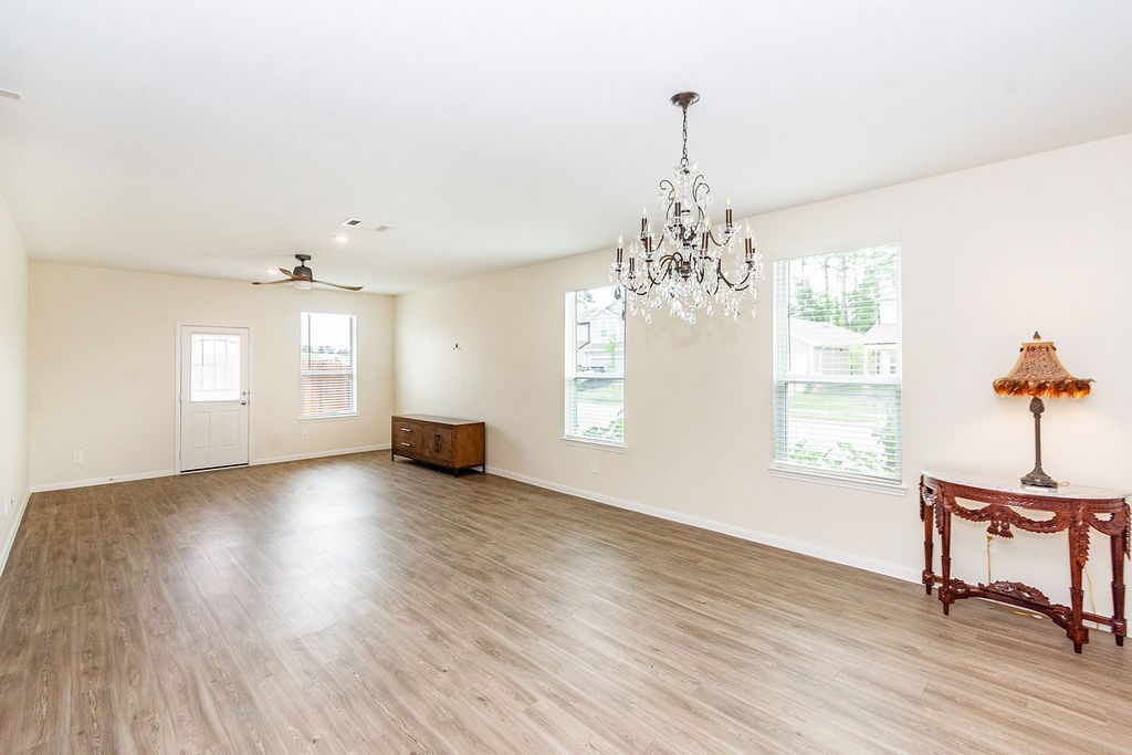 23502 Glenbuck St Spring Spring, TX 77373 - Photo 11 of 50 Spacious living area with hardwood floors, neutral walls, and ample natural light. Features a ceiling fan, chandelier, and decorative furniture, creating a bright and elegant space.