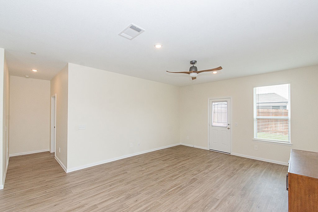 23502 Glenbuck St Spring Spring, TX 77373 - Photo 20 of 50 This photo showcases a spacious, bright room with light-colored walls and wood flooring. It features a modern ceiling fan, large window, and a door leading outside, offering ample natural light.
