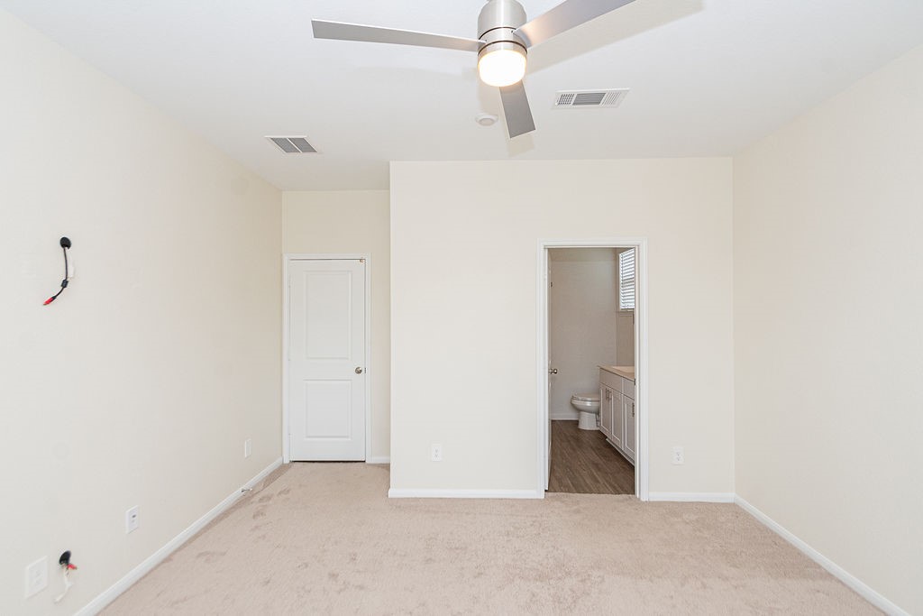 23502 Glenbuck St Spring Spring, TX 77373 - Photo 29 of 50 This room features neutral walls, carpeted flooring, and a ceiling fan. A door leads to an en-suite bathroom with a vanity and toilet.
