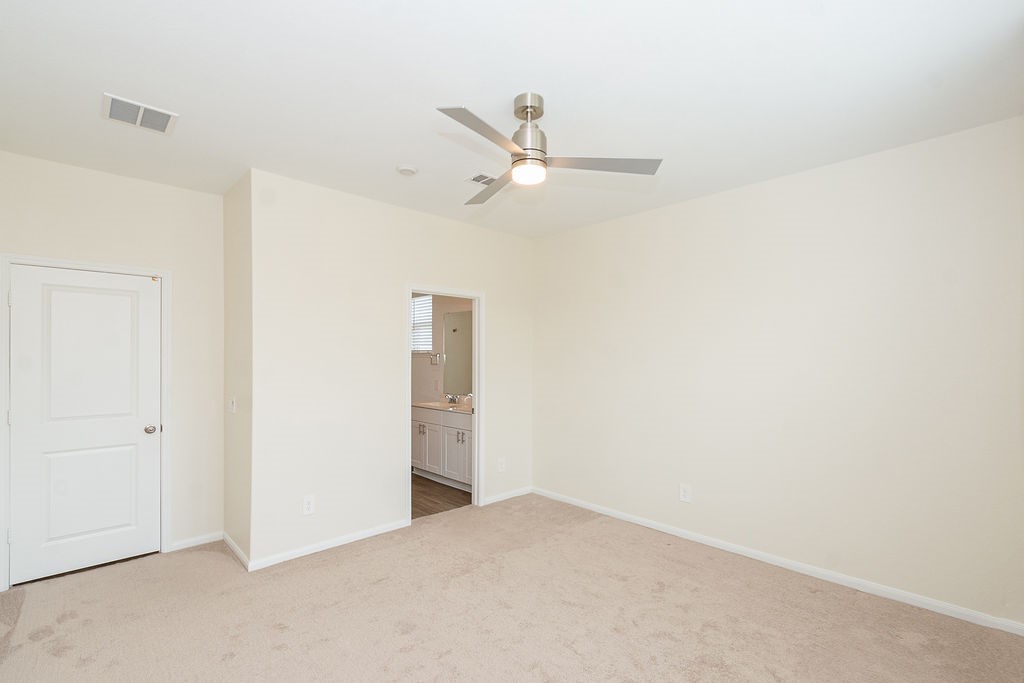 23502 Glenbuck St Spring Spring, TX 77373 - Photo 32 of 50 This room is spacious with neutral-colored walls and carpet, featuring a ceiling fan and access to an en-suite bathroom.