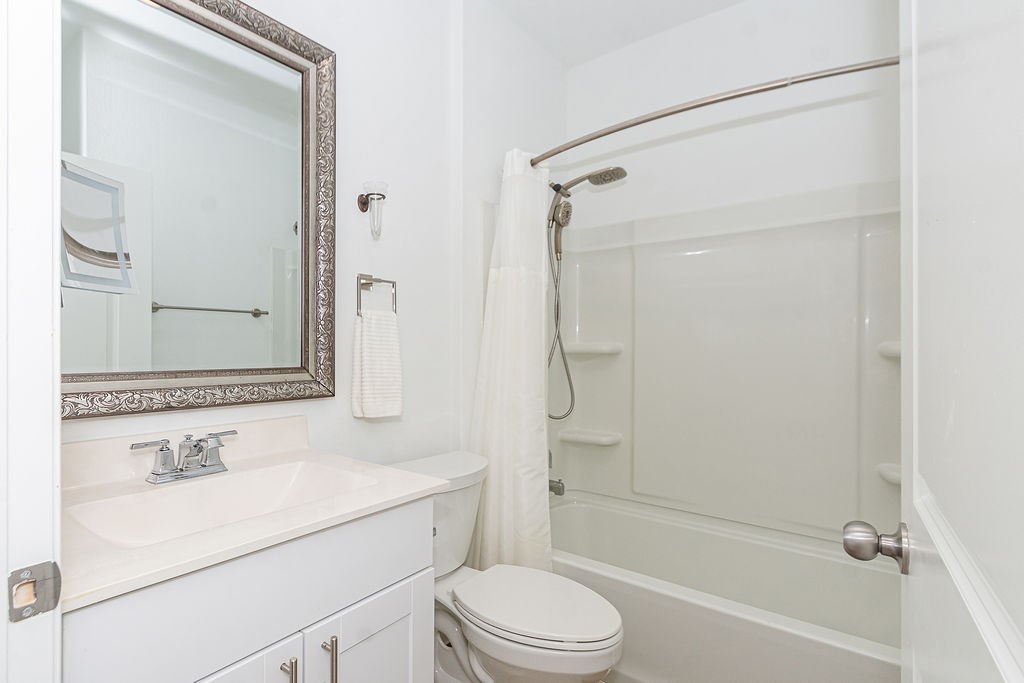 23502 Glenbuck St Spring Spring, TX 77373 - Photo 36 of 50 Bright, modern bathroom featuring a white vanity with a decorative mirror, a clean bathtub-shower combo with a curved curtain rod, and sleek fixtures.