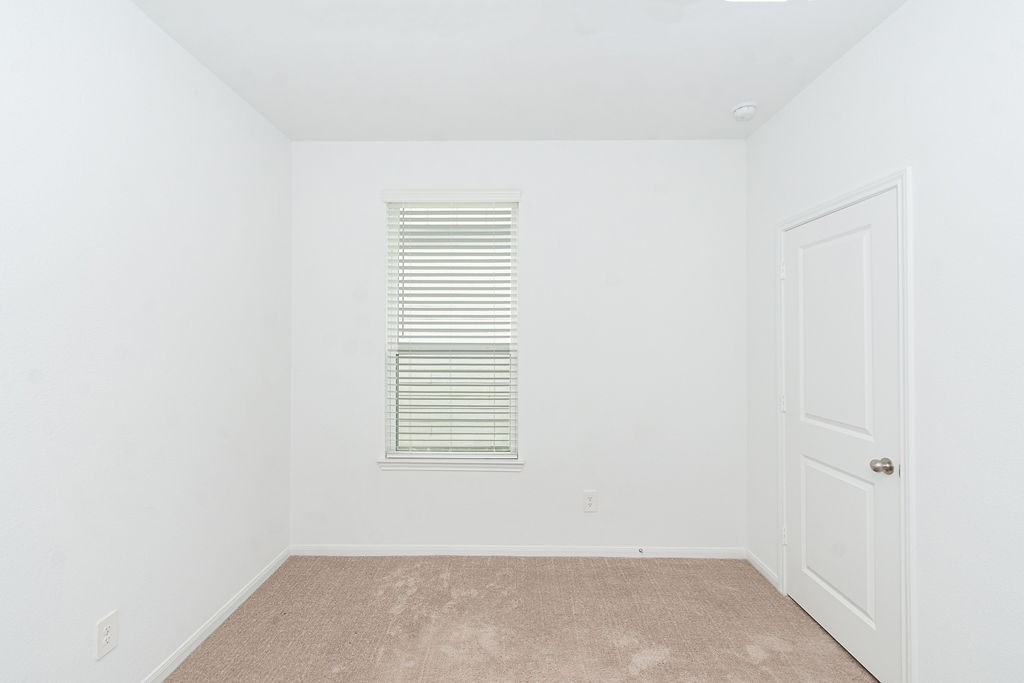 23502 Glenbuck St Spring Spring, TX 77373 - Photo 42 of 50 This room features clean white walls, a single window with blinds for natural light, and a neutral carpeted floor, creating a bright and versatile space.