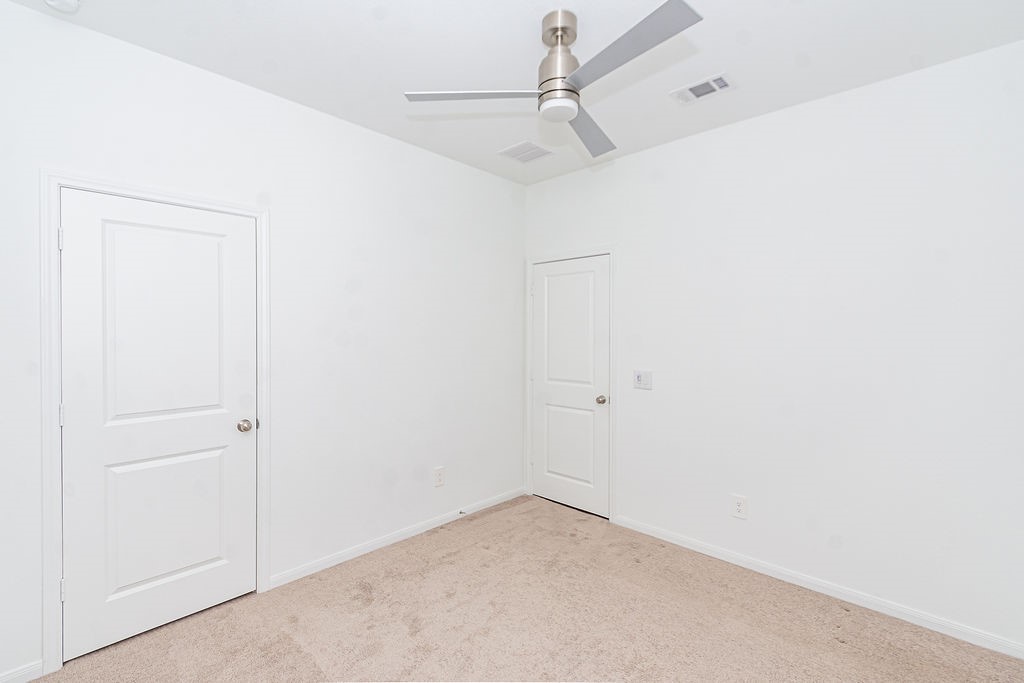23502 Glenbuck St Spring Spring, TX 77373 - Photo 43 of 50 This room features neutral carpeting, white walls, a modern ceiling fan, and two white doors, offering a clean, versatile space ready for customization.