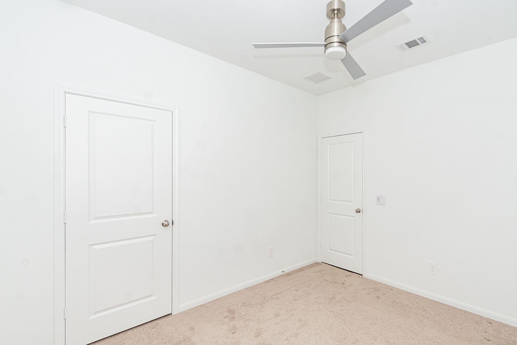 23502 Glenbuck St Spring Spring, TX 77373 - Photo 44 of 50 This room features neutral walls, carpeted flooring, a ceiling fan, and two white doors, offering a clean and versatile space.
