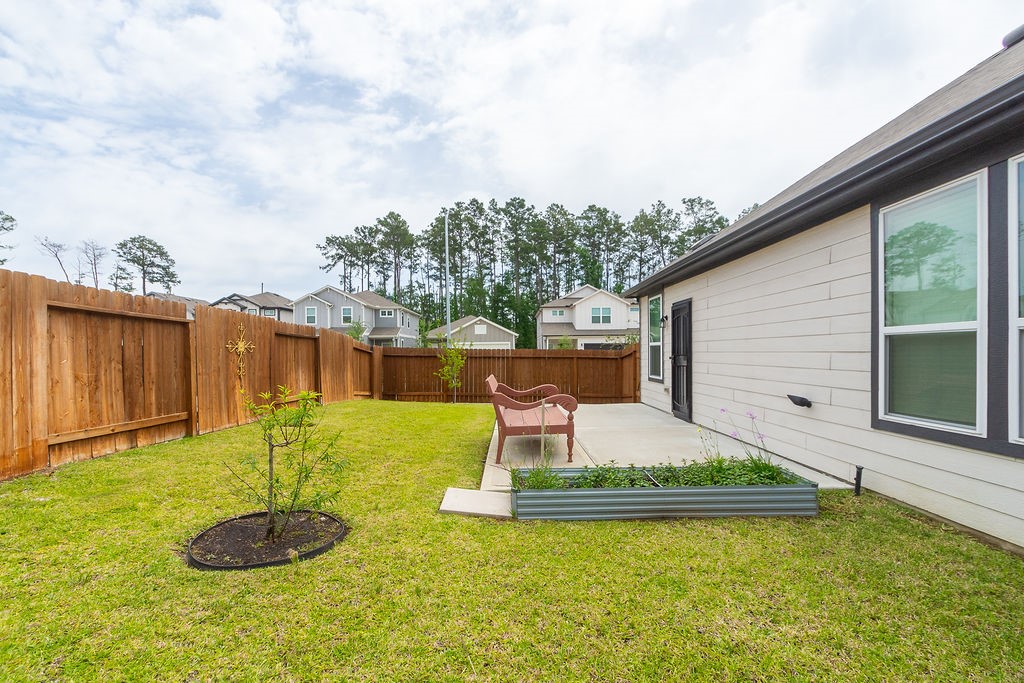 23502 Glenbuck St Spring Spring, TX 77373 - Photo 48 of 50 This photo features a cozy backyard with a well-maintained lawn, a small patio area with a bench, and a wooden privacy fence. Ideal for relaxation and outdoor activities.