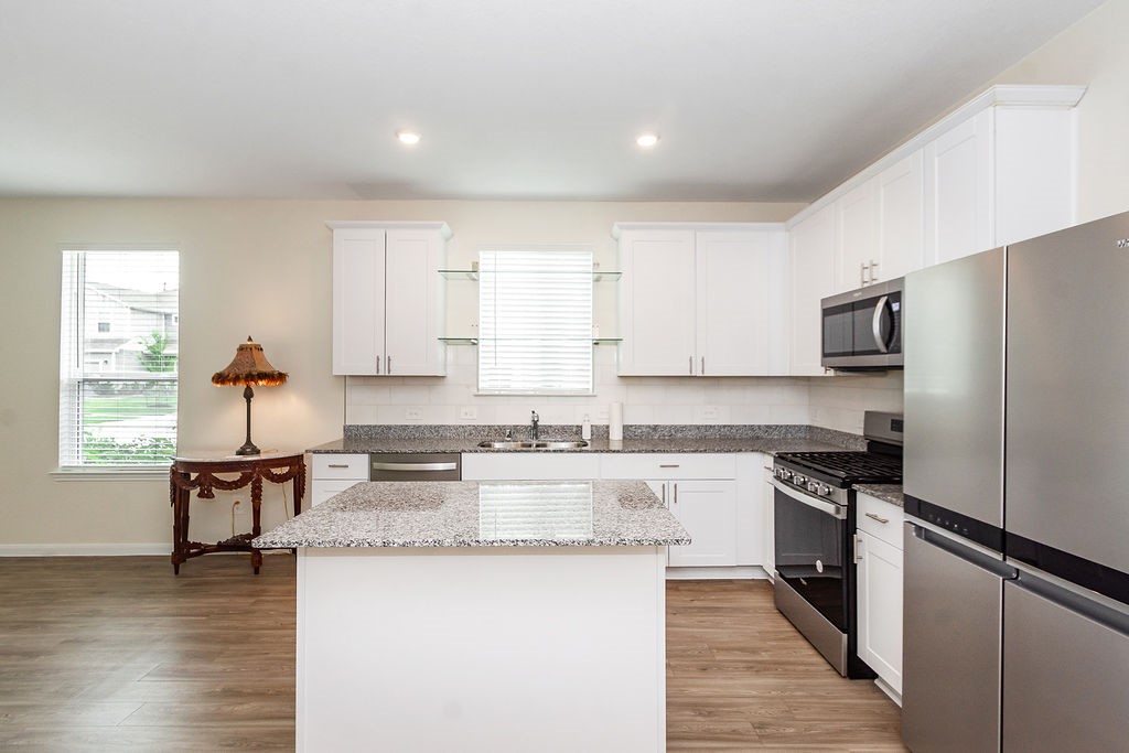 23502 Glenbuck St Spring Spring, TX 77373 - Photo 7 of 50 This modern kitchen features sleek stainless steel appliances, white cabinetry, and a granite island. It has ample natural light from a large window, enhancing the open and airy feel.