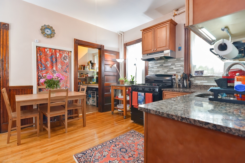 52 Tower Street Boston, MA 02130 - Photo 7 of 29 a kitchen with stainless steel appliances granite countertop a stove top oven a dining table and chairs with wooden floor