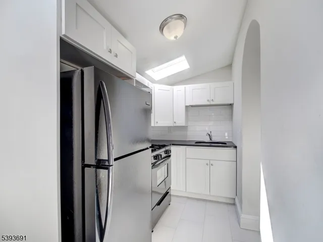 a kitchen with stainless steel appliances granite countertop a sink a stove a refrigerator and white cabinets