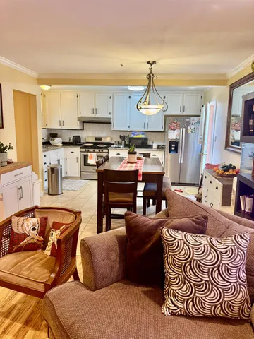 a living room with furniture kitchen view and a window