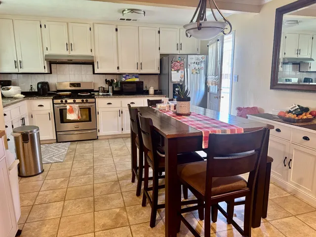 a kitchen with stainless steel appliances granite countertop a sink a stove a table and chairs