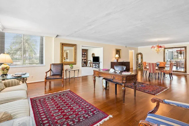 a dining room with wooden floor a chandelier a glass table and chairs