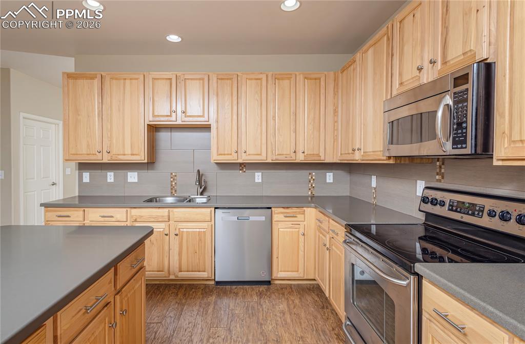 4815 Harrier Ridge Drive Colorado Springs, CO 80916 - Photo 9 of 33 Kitchen featuring stainless steel appliances, light wood finish cabinets, dark wood-style floors, dark countertops, and recessed lighting