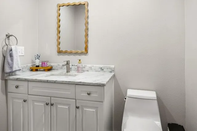 a bathroom with a granite countertop sink and a mirror