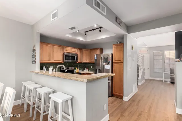 a view of a kitchen with refrigerator and wooden floor