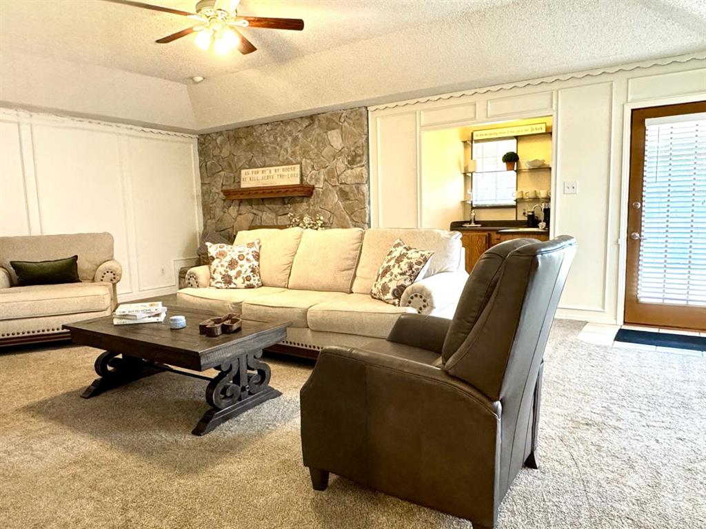 113 Northeast Timber Ridge Drive Burleson, TX 76028 - Photo 6 of 36 Spacious living area featuring a vaulted ceiling with a ceiling fan, stone fireplace, wet bar, and wainscoting detailing.